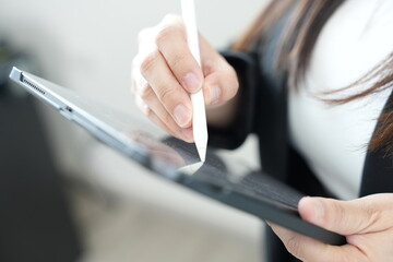 A person using a digital stylus to write or draw on a tablet device, focusing on technology and creativity.