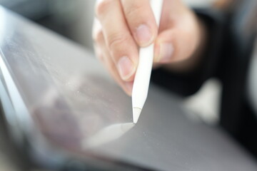 A hand using a digital stylus to write or draw on a tablet screen.