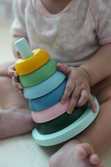 A baby playing with a colorful stacking ring toy while sitting on the floor.