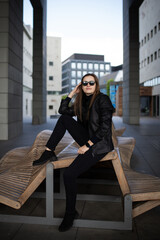 Stylish tech-savvy woman in black outfit posing in urban architecture – lifestyle shoot