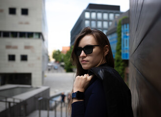Stylish tech-savvy woman in black outfit posing in urban architecture – lifestyle shoot