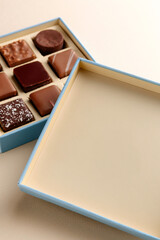 Minimal overhead shot of open box with chocolate squares on beige background, elegant candy dessert packaging mockup concept