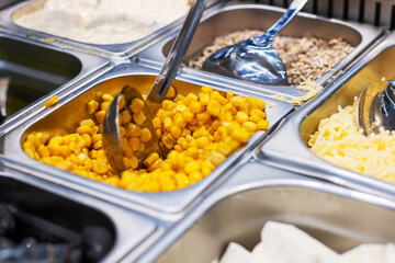 A tray filled with fresh corn is currently being scooped out using a spoon