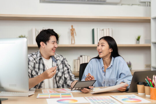 UX and UI Design Teamwork. Young designers sharing insights on color schemes and layouts in an office setting.