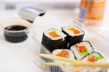 A plastic container filled with delicious sushi and chopsticks