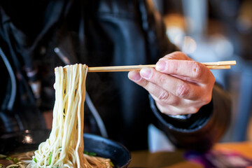 A person is enjoying a bowl of delicious noodles using chopsticks