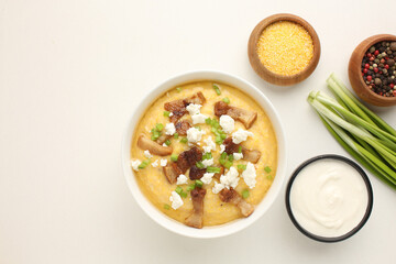 traditional Ukriaina food Corn hominy porridge in a clay pot. Corn flour in a clay bowl and cob of ripe corn. Light background. Close-up. View from above.