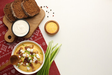 traditional Ukriaina food Corn hominy porridge in a clay pot. Corn flour in a clay bowl and cob of ripe corn. Light background. Close-up. View from above.