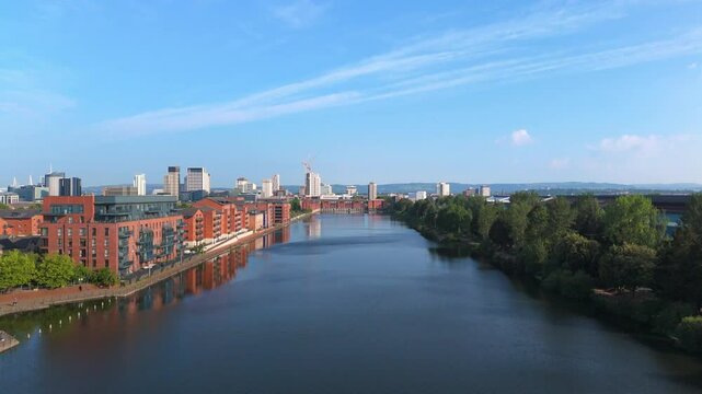 Aerial drone footage of Bute East Dock in the Atlantic Wharf neighbourhood of Cardiff, Wales, with a panoramic view of the city centre in the background. Pedestal up shot.