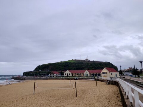 View of Nobby's Beach with volleyball nets and a clubhouse on a cloudy and stormy day