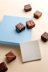 Minimal overhead shot of closed box with blank card on beige background, elegant chocolate packaging mockup concept