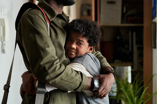 Child and parent sharing an affectionate embrace, with childs smile capturing warmth and happiness. Background of a home setting, highlighting family bond