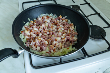 Chopped bacon cooking in a frying pan 