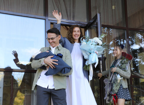 family greets a young mother who gave birth to a baby at her discharge from the maternity hospital