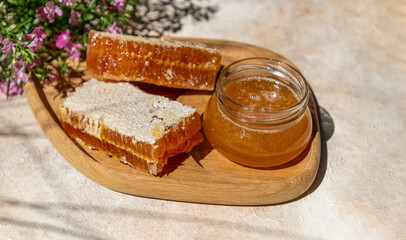 Honey Jar and Honeycomb on Wooden Board. Natural sunlight and long shadows. 