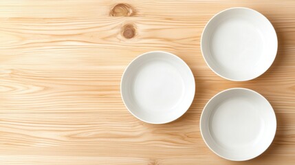 Three empty white plates on a wooden table.