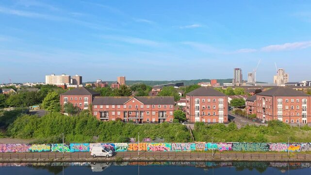 Aerial drone footage of the Atlantic Wharf neighbourhood in Cardiff, Wales flying above the Bute East Dock. Slow motion parallel tracking shot moving right to left above the dock.