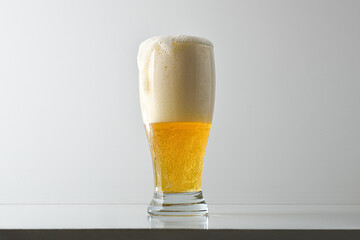 Glass of foamy beer on table and white isolated background