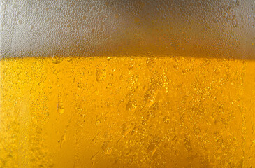 Macro of beer surface and foam in glass with drops