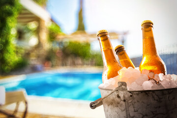 Beers in ice buckets in a garden with a pool