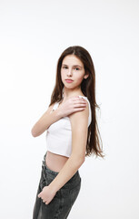 A brunette girl in a white tank top on a white background.,