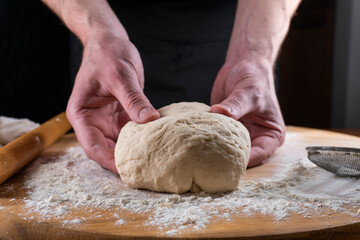 Baking concept. Man preparing dough, kneading dough on wooden table. Man cook baking bread. Close up