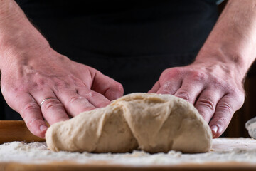 Baking concept. Man preparing dough, kneading dough on wooden table. Man cook baking bread. Close up