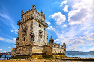 Lisbon, Portugal. Tower Belem at coast of river Tagus. Stones and mussels day during low tide. Sunny blue sky with clouds.