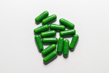 A cluster of vibrant green capsules, arranged on a clean white background.