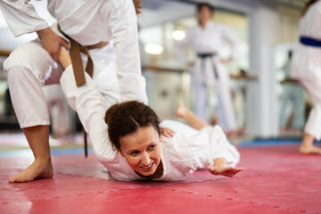 Diligent womens practicing new karate moves in pairs in class with trainer