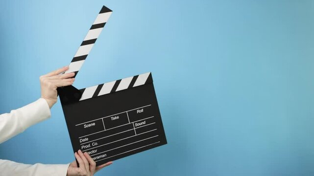 Director's hands using a clapperboard, indicating scene, take, and motion in a movie