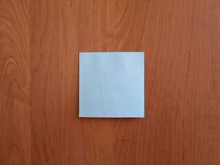 Blank square blue note paper on wooden surface. Note for notes and reminders