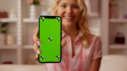 Portrait Caucasian teen girl teenager woman female showing green screen mobile phone excited in candy pink bathroom smiling looking at camera happy positive holding smartphone with chroma key display