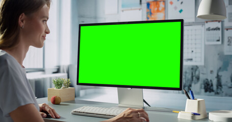 White Female Engineer Operates Desktop Computer With Green Screen in an Office. Workspace Is...