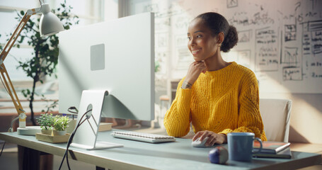 Woman in Yellow Sweater Engages With Her Creative Workspace, Using Computer. Professional Doing...