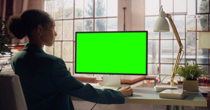 Screen Computer Monitor standing on the desk in Bright Creative Workspace Office. Chroma key Display. Modern Interior with Warm Minimalistic Background, Window with Park Outside