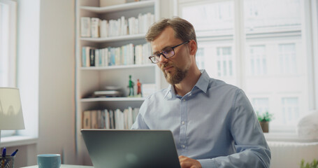Creative Man Works on His Laptop at a Desk. Professional Marketing Writer Deep in Thought, Analysis...