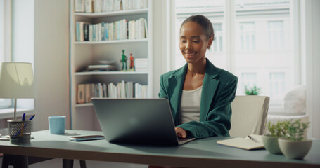 African American Woman Works on Laptop in Bright Home Office. Radiant Smile Illuminates Her Face, Professional Success and Personal Fulfillment in Style and Productivity. Bright Apartment