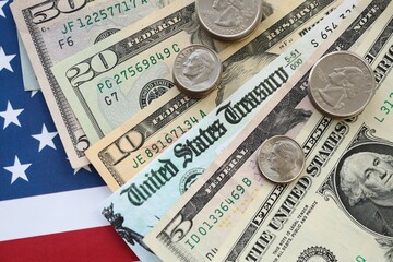 American US dollars money bills and coins with stimulus bill or refund check on American flag