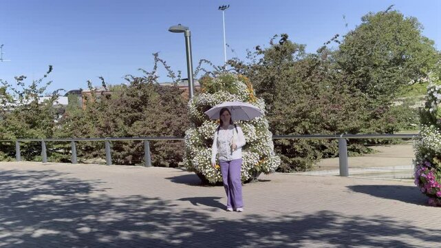 Woman walking with parasol in Rosaleda Juan Carlos I park in Malaga