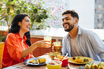 Smiling friends enjoying a meal and drinks together outdoors on a sunny day