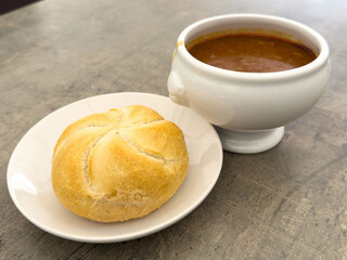 Rustic bread roll with hearty bowl of soup on a stone table