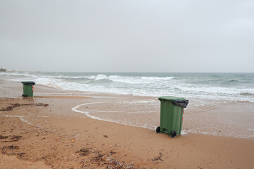 Waste management on the coast trash bins near the waterline on an empty shore