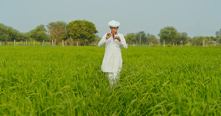 Indian farmer man standing hold wooden flute playing woodwind music outdoor farmland old aged...