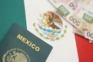 Mexican pesos money bills in big amount and passport lies on Mexico flag close up