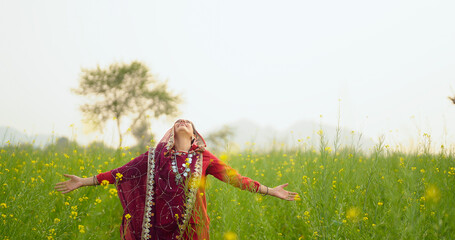 Indian adult gen x beautiful model woman lady wear red traditional saree enjoy outdoor nature Asian smiling relax female looking up feeling happy yellow flower