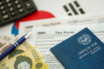 South Korean won money bills lies on table with pen, calculator, passport and tax forms