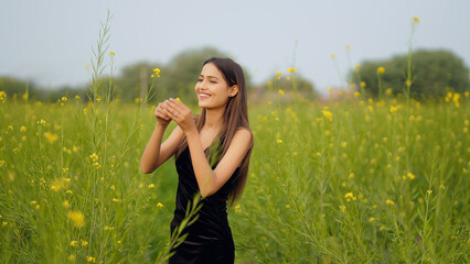 Indian happy young adult gen z model woman lady wear black dress standing outdoor enjoy nature...