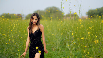 Indian happy young adult gen z model lady woman wear black dress outdoor garden enjoy nature asian...