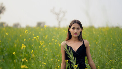 Indian happy young adult gen z model lady woman wear black dress outdoor garden enjoy nature asian...